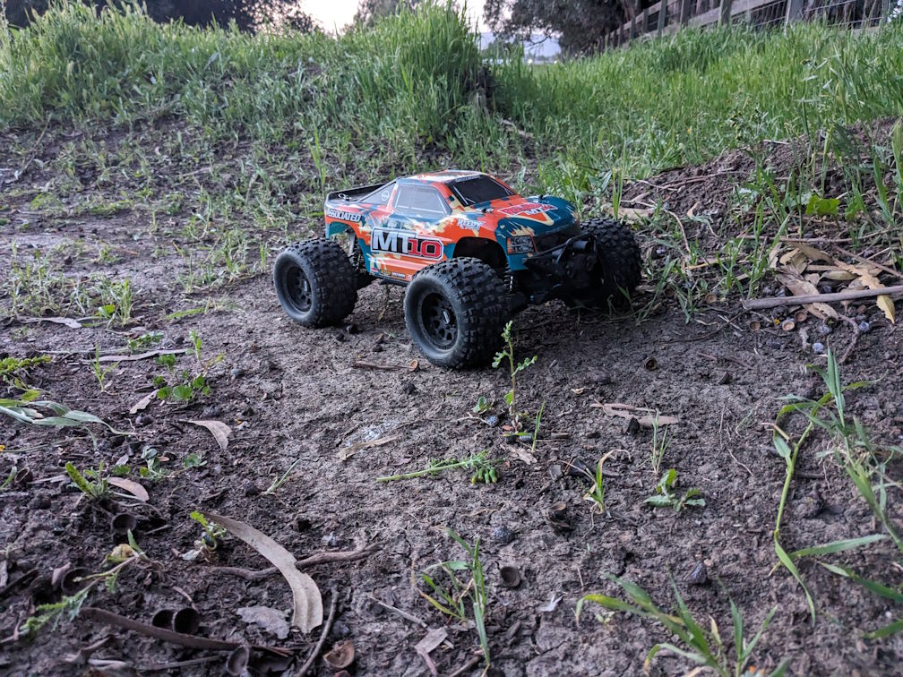 a photo of a team associated Rival MT10 monster truck on a grassy dirt track