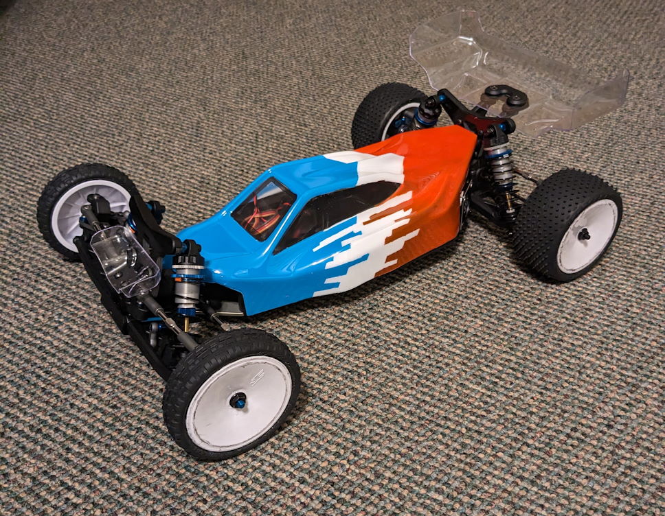 a photo of a orange, white and blue B7 RC race buggy