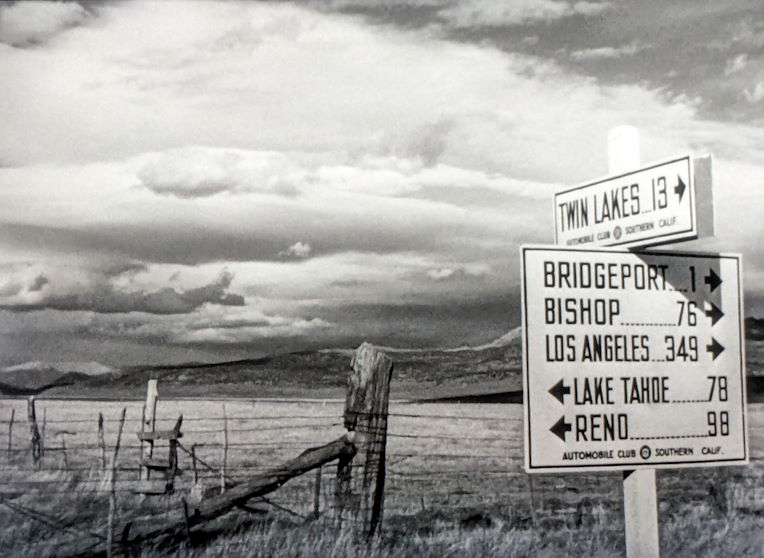 a road sign with distances to Bishop, Tahoe, and other locations in the Eastern Sierras by Bridgeport from Out of the Past
